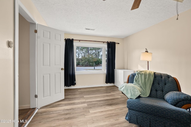 sitting room with visible vents, a ceiling fan, a textured ceiling, light wood-style floors, and baseboards