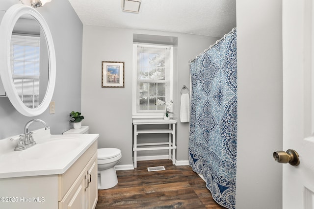 bathroom with vanity, wood finished floors, visible vents, a textured ceiling, and toilet