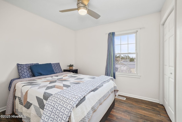 bedroom featuring a ceiling fan, dark wood-style floors, visible vents, baseboards, and a closet