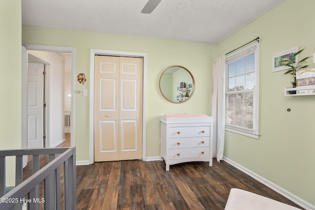 unfurnished bedroom featuring a closet, baseboards, a textured ceiling, and dark wood-style flooring