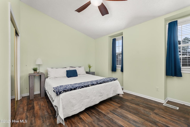 bedroom with visible vents, baseboards, lofted ceiling, wood finished floors, and a closet