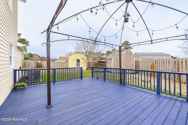 deck with a yard, a shed, an outdoor structure, and a fenced backyard