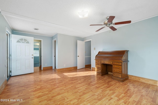 interior space featuring light wood-style floors, ornamental molding, a textured ceiling, and baseboards