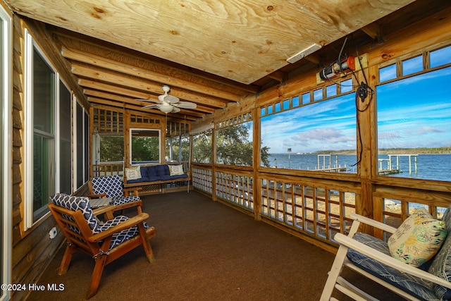 sunroom / solarium featuring ceiling fan and a water view