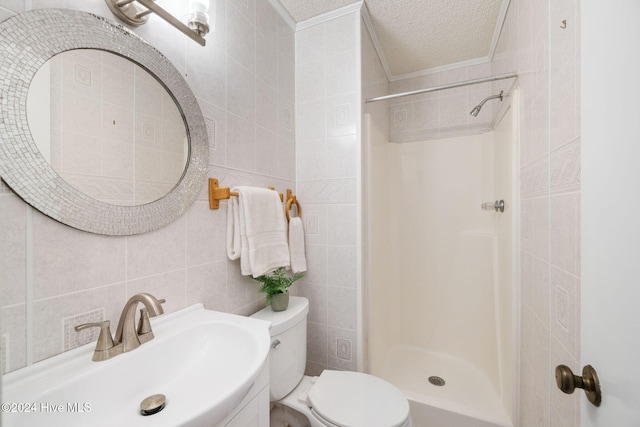 bathroom featuring tile walls, toilet, a sink, a shower stall, and a textured ceiling