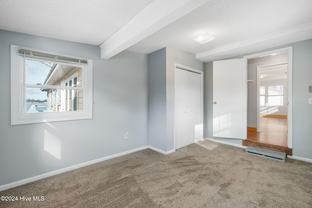 interior space with carpet, beam ceiling, baseboards, and a textured ceiling