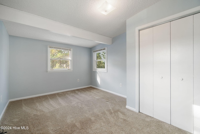 unfurnished bedroom featuring a closet, a textured ceiling, baseboards, and carpet flooring