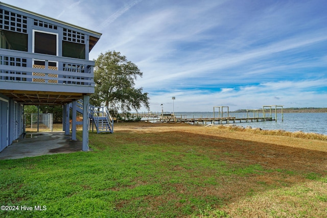 view of yard featuring a boat dock, a patio area, stairway, and a deck with water view