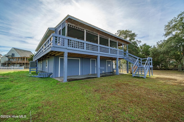 rear view of property featuring board and batten siding, a yard, stairway, and fence