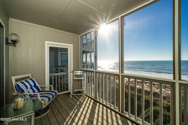 unfurnished sunroom with a view of the beach and a water view