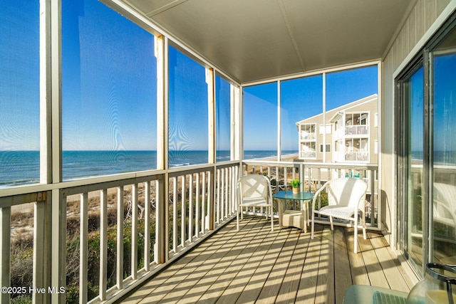 unfurnished sunroom with a water view and a beach view