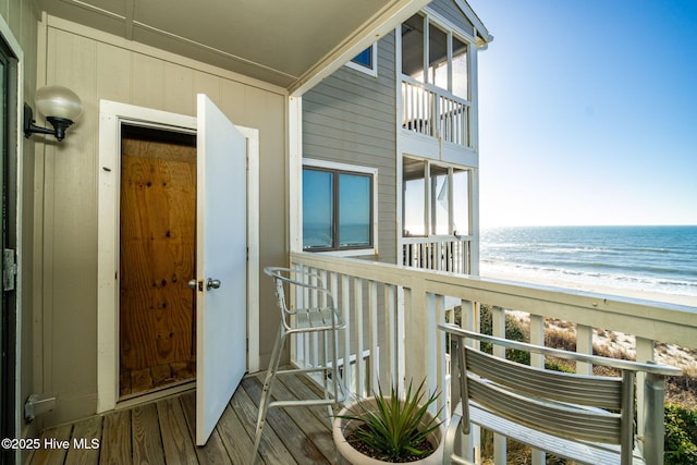 balcony with a water view and a view of the beach