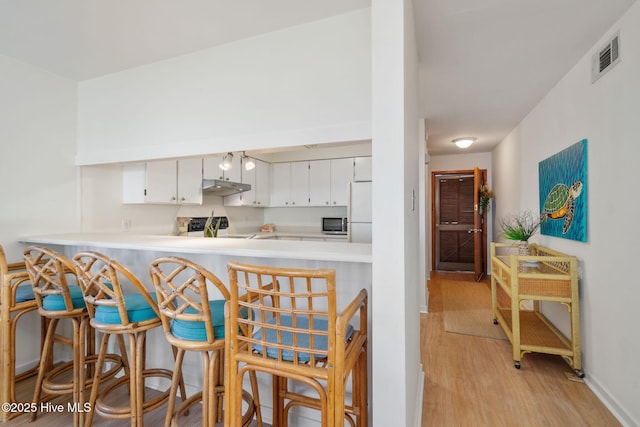 kitchen featuring electric range, white refrigerator, light wood-type flooring, kitchen peninsula, and white cabinets