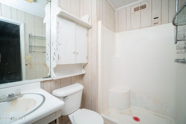 bathroom with toilet, vanity, wooden walls, a shower, and ornamental molding