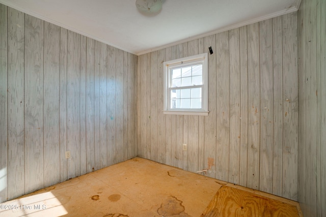 unfurnished room featuring crown molding and wood walls