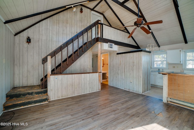 unfurnished living room with wood ceiling, wood-type flooring, vaulted ceiling with beams, and wooden walls