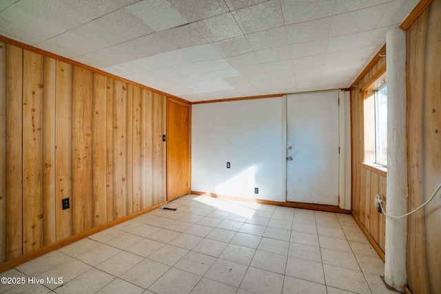 tiled spare room featuring wood walls