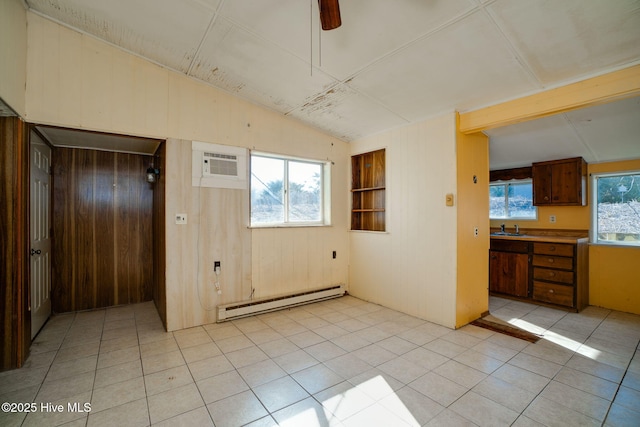 interior space featuring lofted ceiling, sink, baseboard heating, a wall unit AC, and wood walls