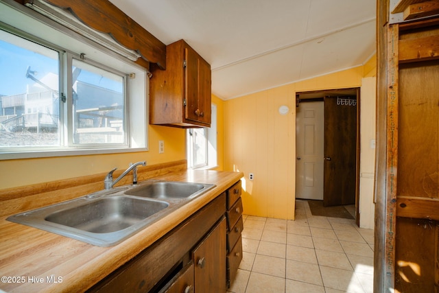 kitchen featuring sink, light tile patterned floors, and vaulted ceiling