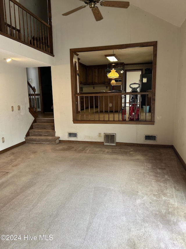 unfurnished living room with ceiling fan, carpet floors, and lofted ceiling