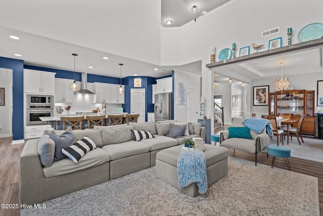 living room with light hardwood / wood-style floors and a towering ceiling