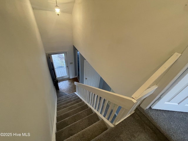 stairway featuring carpet floors and a high ceiling