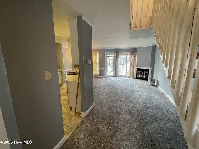 unfurnished living room featuring crown molding, sink, and light carpet