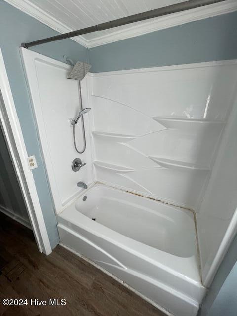 bathroom with wood-type flooring, ornamental molding, and bathing tub / shower combination