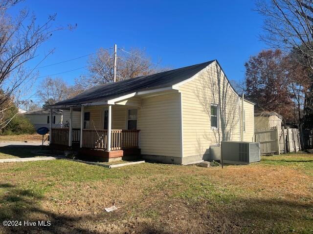 view of property exterior featuring central AC, a yard, and a porch