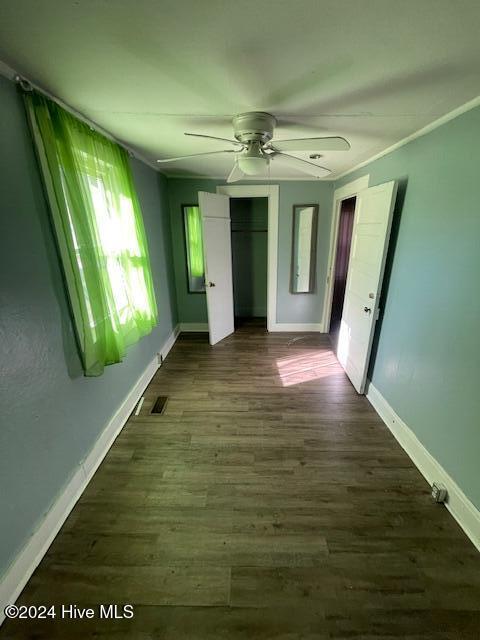 unfurnished bedroom with a closet, ceiling fan, and dark wood-type flooring