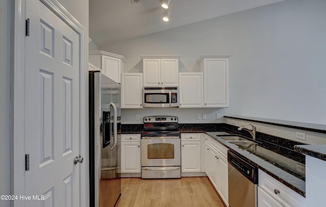 kitchen featuring appliances with stainless steel finishes, vaulted ceiling, light hardwood / wood-style flooring, dark stone countertops, and white cabinets