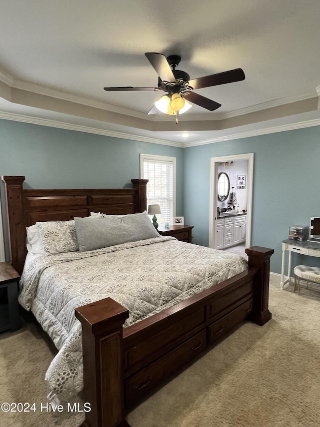 bedroom featuring connected bathroom, ceiling fan, a tray ceiling, light carpet, and ornamental molding