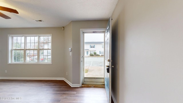 doorway featuring hardwood / wood-style flooring, ceiling fan, and a textured ceiling