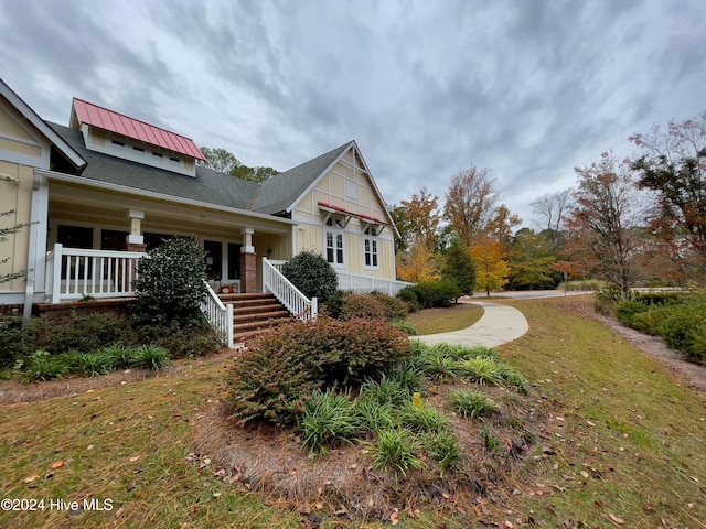 view of side of home featuring a porch and a lawn