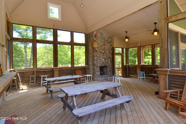 interior space with a stone fireplace, ceiling fan, and vaulted ceiling