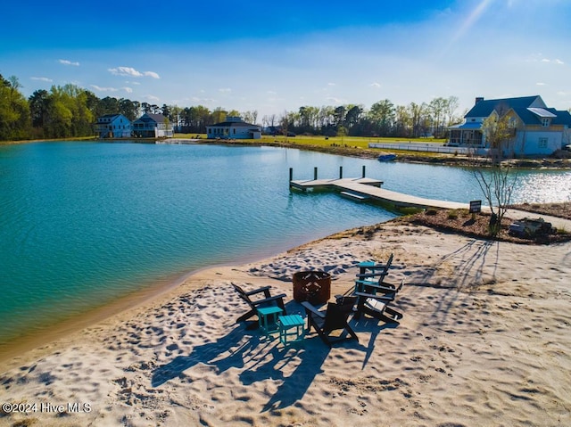 view of dock with a water view and a beach view