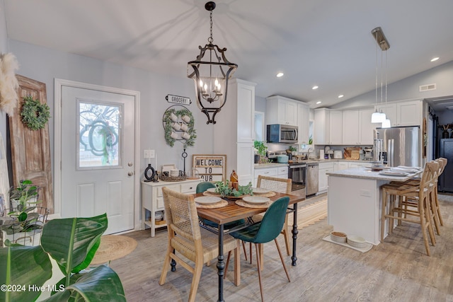 dining space featuring a notable chandelier, lofted ceiling, sink, and light hardwood / wood-style flooring