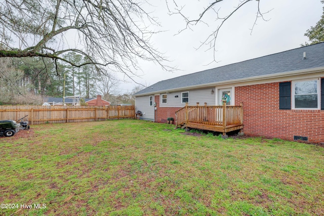 rear view of house featuring a lawn and a deck