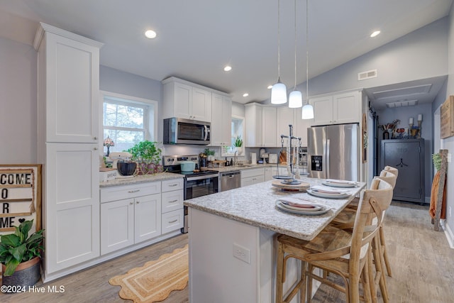 kitchen featuring stainless steel appliances, pendant lighting, white cabinets, a kitchen island, and lofted ceiling