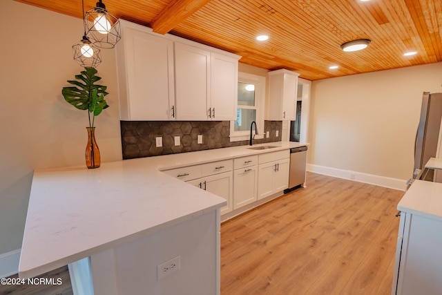 kitchen with stainless steel appliances, sink, white cabinetry, decorative light fixtures, and backsplash