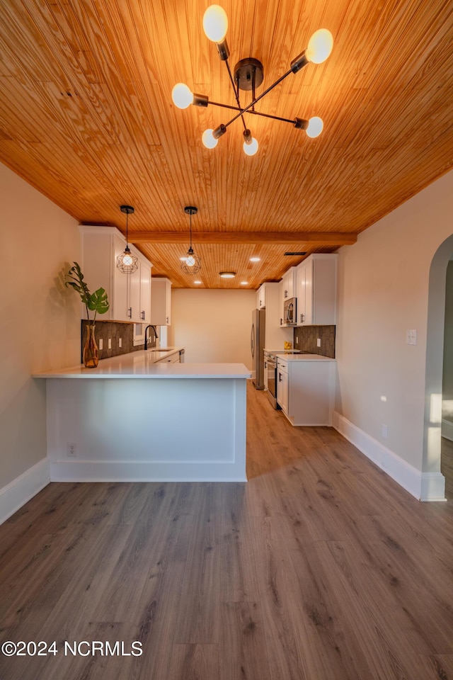 kitchen with stainless steel appliances, decorative light fixtures, white cabinets, kitchen peninsula, and backsplash