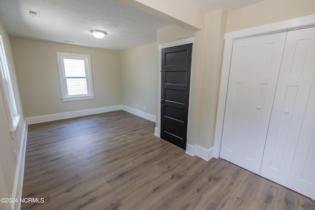 unfurnished bedroom with dark hardwood / wood-style flooring and a closet