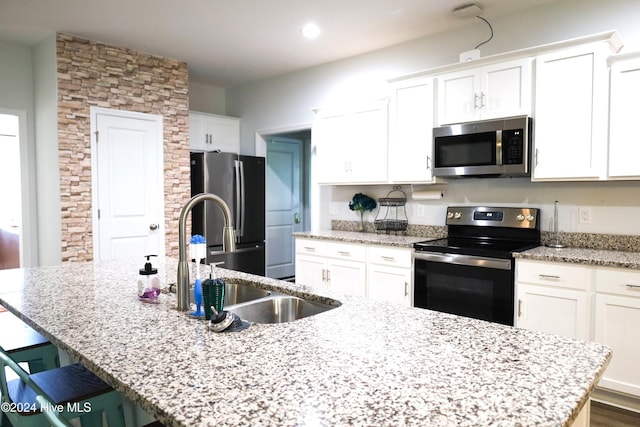 kitchen featuring a center island with sink, white cabinets, and stainless steel appliances