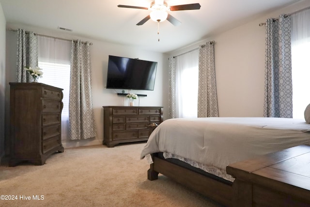 bedroom featuring multiple windows, ceiling fan, and light carpet