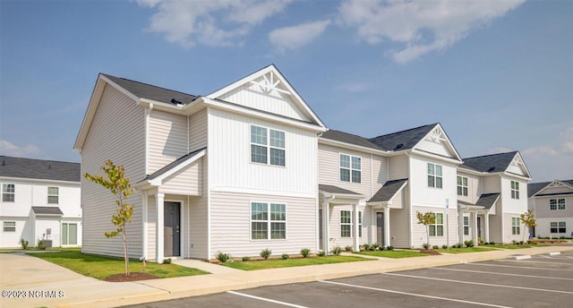 townhome / multi-family property with uncovered parking, a residential view, and board and batten siding