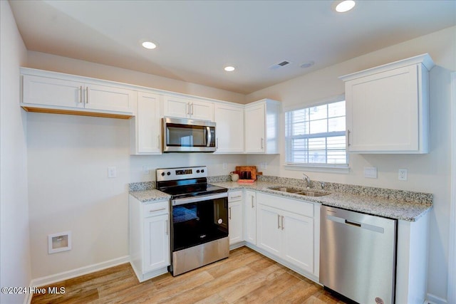 kitchen with white cabinets, stainless steel appliances, light hardwood / wood-style floors, and sink