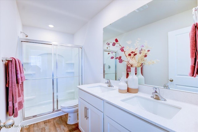 bathroom featuring hardwood / wood-style flooring, vanity, toilet, and a shower with door