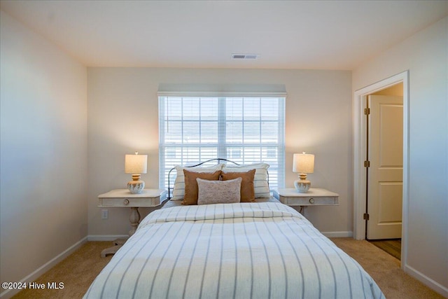 bedroom with baseboards, visible vents, and light colored carpet