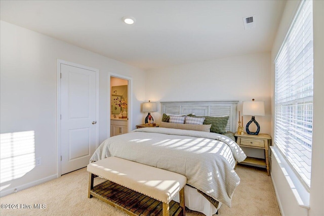 bedroom featuring ensuite bathroom and light colored carpet