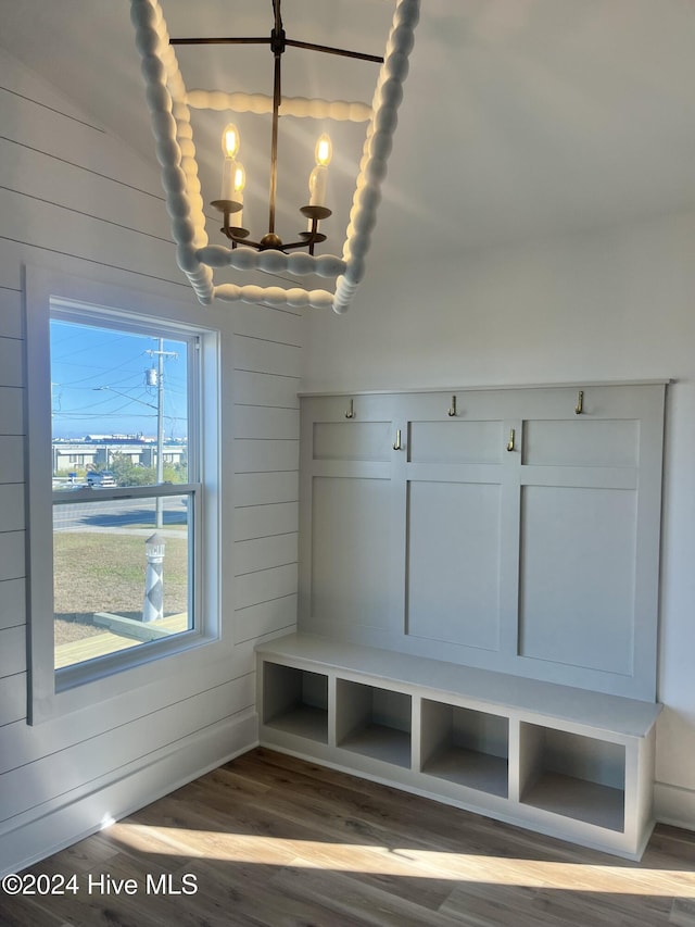 mudroom featuring hardwood / wood-style floors, wooden walls, and an inviting chandelier